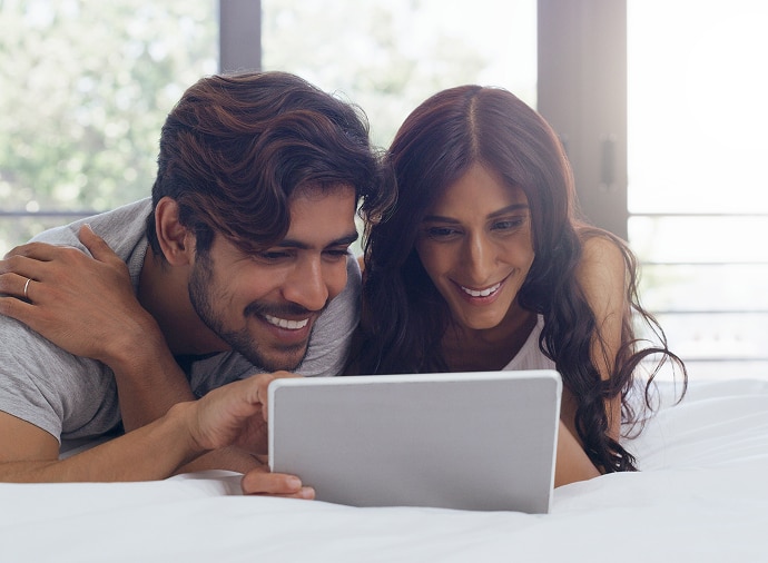 Un uomo e una donna ridono mentre guardano un tablet